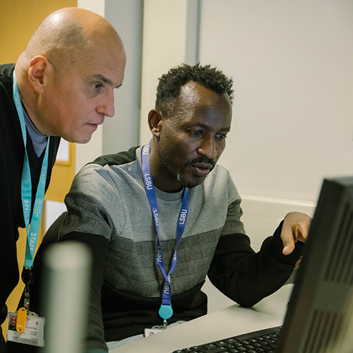 Two men wearing LSBU lanyards are looking at a screen for results